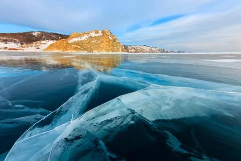 The cross of deep cracks in the thick ice of the winter lake Baikal opposite the Stock Photos