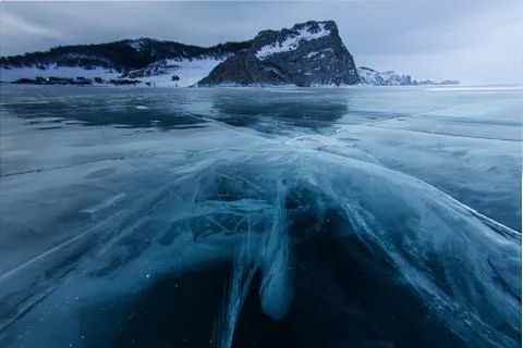 The cross of deep cracks in the thick ice of the winter lake Baikal opposite the Stock Photos