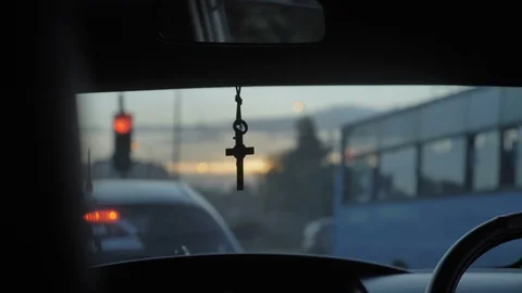 A cross hanging on a mirror of a moving car through a city traffic Stock Footage 109239805