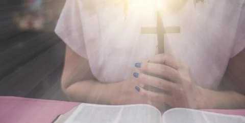 A cross is held in hands with the opened bible Photos