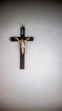 A cross hung on a white wall Stock Photos