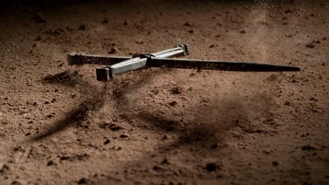 Cross made of nails falling onto dusty surface.  Shot with Phantom Flex 4K Stock Footage 130357123
