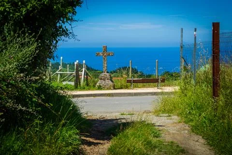 Cross made of stone against the backdrop of the Atlantic Ocean, the road leading Stock Photos