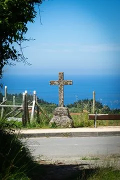 Cross made of stone against the backdrop of the Atlantic Ocean, the road leading Stock Photos