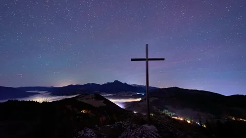 Cross on Mountain Peak at Night under Starry Sky with Cloud Inversion 動画素材 325435559