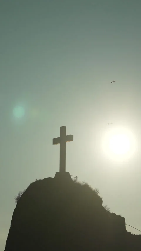 Cross, mountain, sunset a large cross stands on a peak with birds flying against Stock Footage 318387044