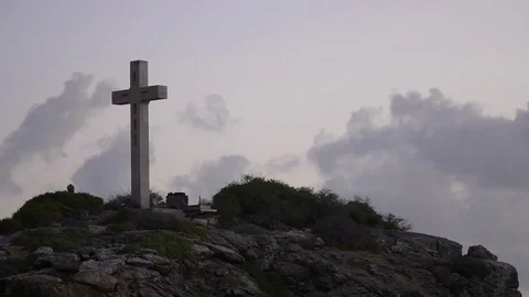 Cross mounted on a rocky cliff with grass around it Stock Footage 77803929