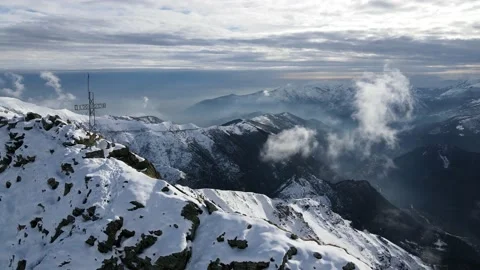 Cross on the peak of the mountain, some snow and clouds moving fast. Alps 4K Stock Footage 148031153