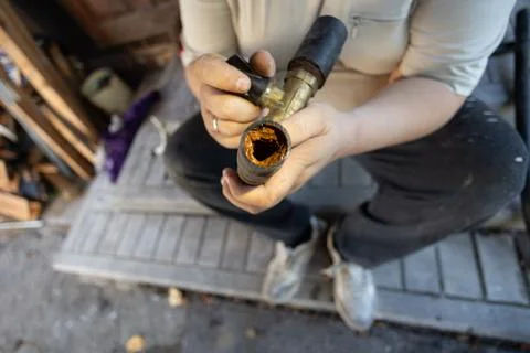 A cross-section of an old clogged water pipe A man holds a section of an old Stock Photos