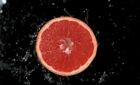 A cross-section of a red grapefruit is suspended in midair against Stock Photos