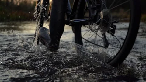 Cross a small mountain river on a mountain bike in the rays of the setting sun. Stock Footage 144441810