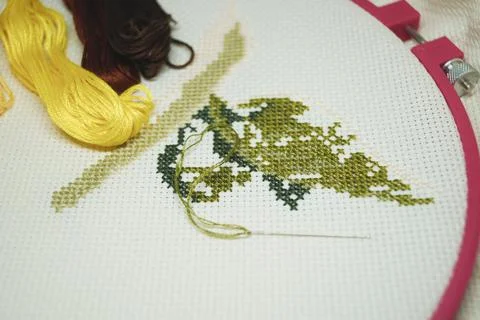 Cross-stitch with colored threads on a white canvas hobby craft  Stock Photos