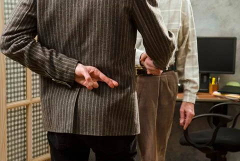 Crossed fingers while shaking hands Stock Photos