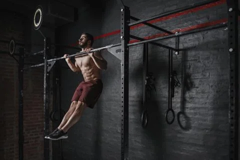 Crossfit athlete doing pull-ups at the gym. Practicing calisthenics. Handsome Stock Photos