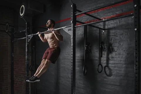 Crossfit athlete doing pull-ups at the gym Stock Photos