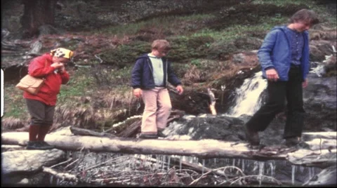 Crossing a mountain stream over a tree log, 1970s (vintage 8 mm amateur film) Stock Footage 7769280