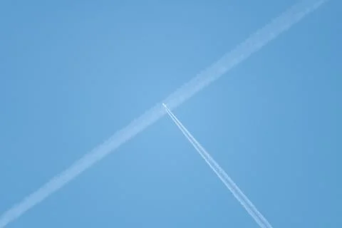 Crossing of plane trails in the blue sky Stock Photos