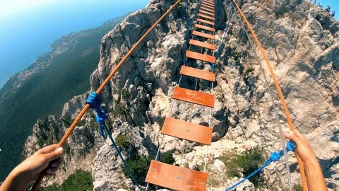 Crossing the rope bridge between the rocks.Extreme tourism.Sense of danger. Stock Footage 95548867