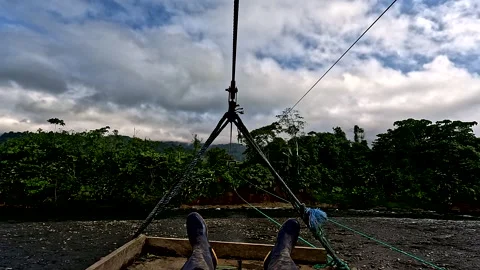 Crossing a tropical river while lying on a handmade small wooden platform 库存影片 336933772