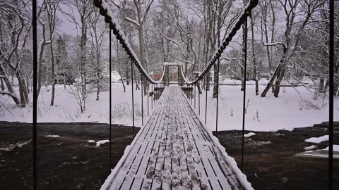 Crossing a winter river through a snowy suspension bridge with strong chains. Stock Footage 236313276