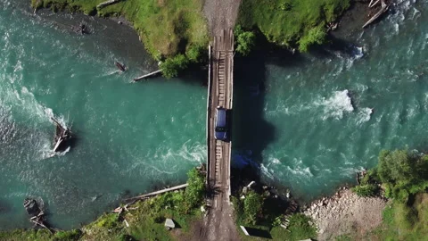 Crossover SUV car driving on old wooden bridge with planks through mountain Vidéo 130299870