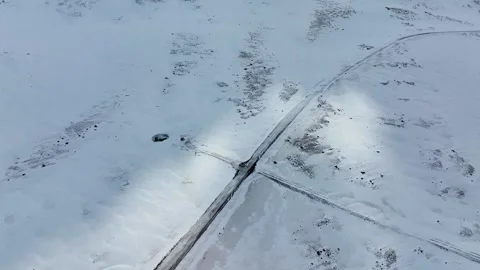 Crossroads cuts through vast snow-covered plain, dark sunbeam patches Stock Footage 338427932