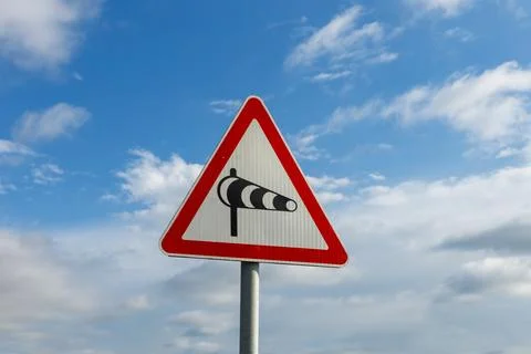 Crosswind caution sign warns drivers of potential hazards on roads Stock Photos
