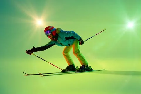 Crouched low, skier glides forward with skis angled slightly against bright Stock Photos