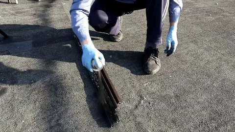 Crouched man in blue gloves paints metal parts with black paint from balonchik Video stock 89434546