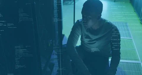 Crouching technician inspecting racks in server room, with blinking LEDs and 写真素材