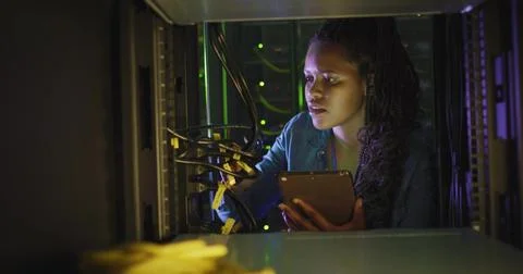 Crouching technician managing network switches and Ethernet cables in LED lit Stock Photos