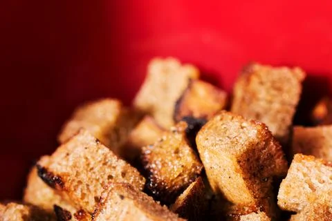 Croutons from black bread on red background. Delicious Fried crunchy crackers Stock Photos