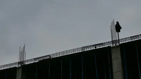 Crow on rebar with worker’s coat flapping in wind on building site Stock Footage 317827126