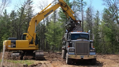 CROW WING CO, MN - 10 MAY 2023: Excavator empties dirt scoop into truck Video stock 250652716