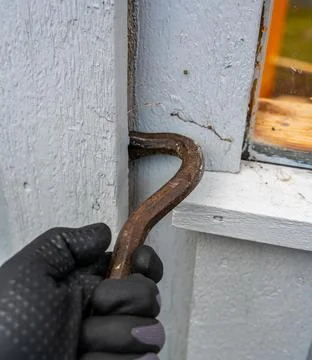 Crowbar held in hands while breaking down the wooden wall. Stock Photos
