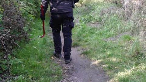 Crowbar. A man walks along a path with a crowbar in his hands. Stock Footage 307043373