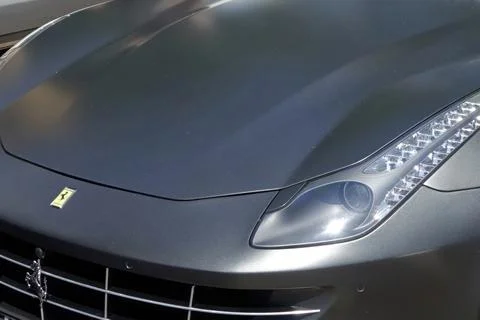 Crowd Admiring a Sleek Matte-Gray Ferrari FF Sports Car at a Lively Outdoor.. Stock Photos