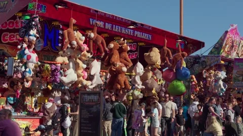 Crowd browsing carnival game booth with hanging stuffed plush toys at outdoor Video stock 348178659