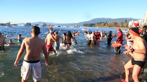 Crowd entering cold ocean water screaming, polar bear swim Stock Footage 58756314