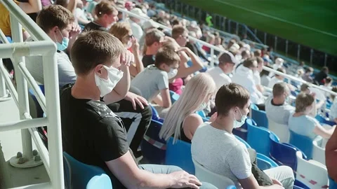 A crowd of fans sitting in the stadium in medical masks and watching a match Stock Footage