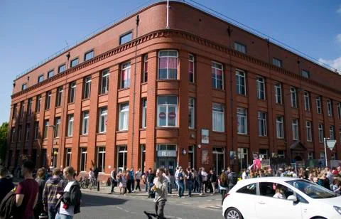 Crowd in front of large red brick building. Stock Photos