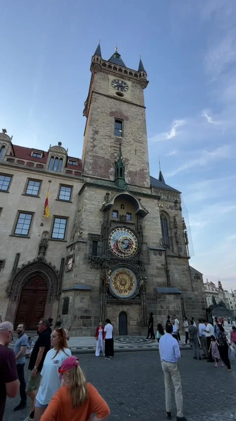 Crowd gathering in historic square before ornate astronomical clock tower at Stock Footage 344584993