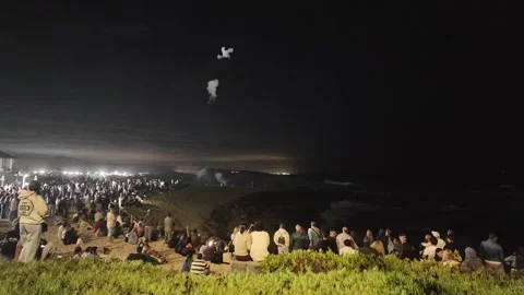 A crowd gathers on the coast to watch a fireworks display during a festival at P Stock Footage 344829826