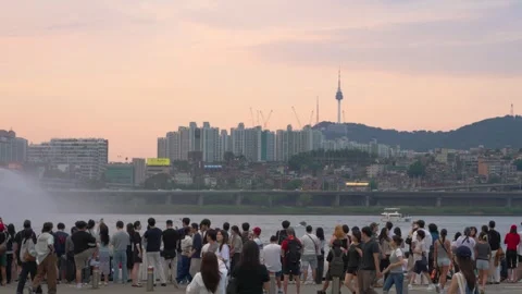 Crowd Gathers by Han River as N Seoul Tower Rises at Sunset Stock Footage 340889570