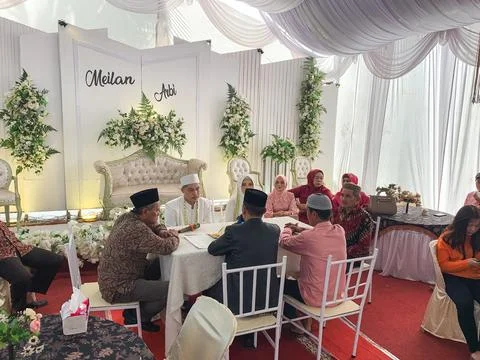 A crowd of guests sitting at round tables during an indoor traditional wedd.. Stock Photos