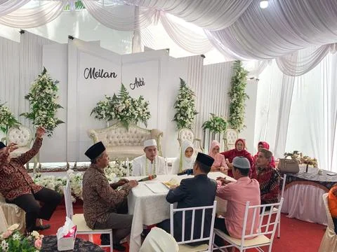 A crowd of guests sitting at round tables during an indoor traditional wedd.. Stock Photos