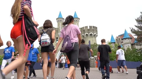 Crowd inside an amusement park walking towards a fake castle Stock Footage 113110712