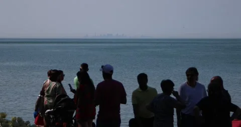 Crowd at lakeshore with distant Toronto skyline on hazy summer day Stock Footage 321035606