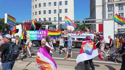Crowd marching with rainbow flags past float on city street parade Vidéo 331448726