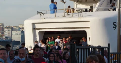 A crowd of passengers comes ashore from a large white ferry moored at the Stock Footage 231717157